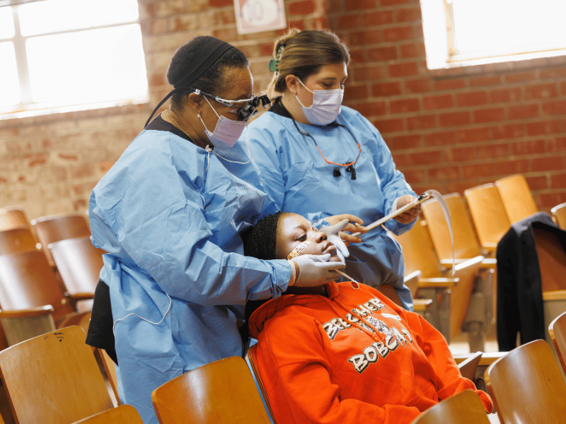 Dr. Teresa Perkins, professor of pediatric dentistry examines ninth-grade student Shunevia Whiting with McKenzi Mcquaig, dental hygiene instructor.