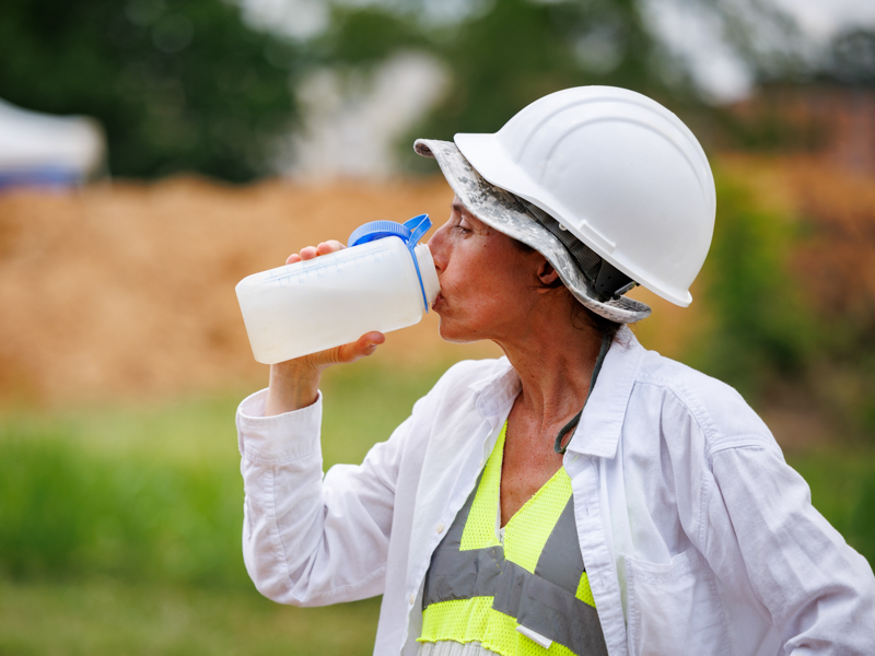 Lead Bioarchaeologist Jennifer Mack pauses for a drink of water while working at the Asylum Hill Project site on campus. Mack's team and others braving the elements this week will experience "feel like" temperatures well over 100 degrees.