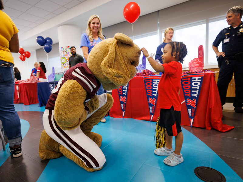 Children's of Mississippi patient Layden McFarland of Greenville pets Bully during a Friends of Children's Hospital Tailgate Party.