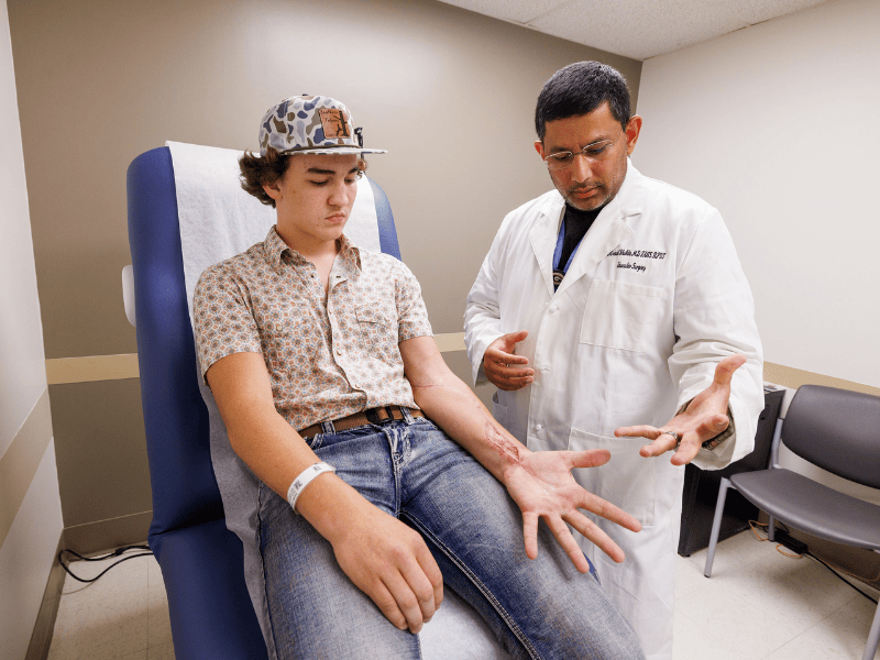 Dr. Mrinal Shukla, professor of surgery and vascular surgeon, examines Tripp Pender's dexterity after surgery.