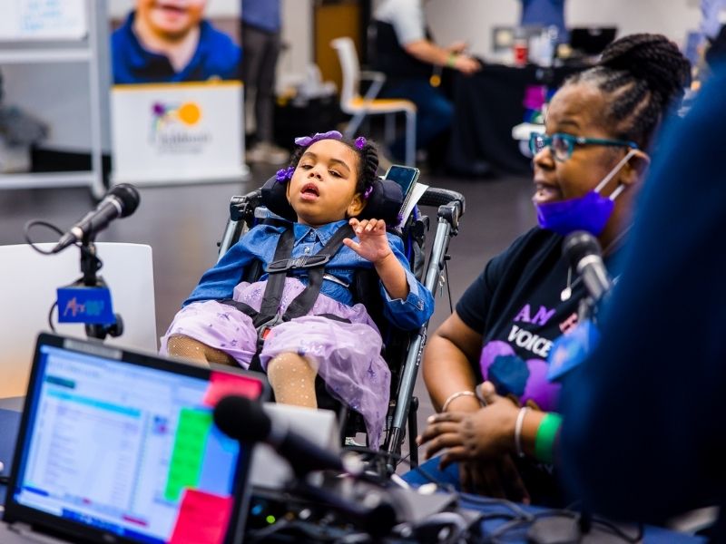 Children's of Mississippi patient Lundyn Roberts listens as mom Nikita talks with broadcasters during the 2022 Mississippi Miracles Radiothon.