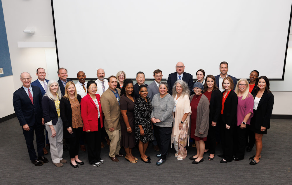 Of the 26 faculty members inducted into The Academy for Excellence in Education last week, 24 initiates are present for the induction ceremony. With them, at far left, is Dr. Scott Rodgers, associate vice chancellor for academic affairs, whose office established the academy in 2022.