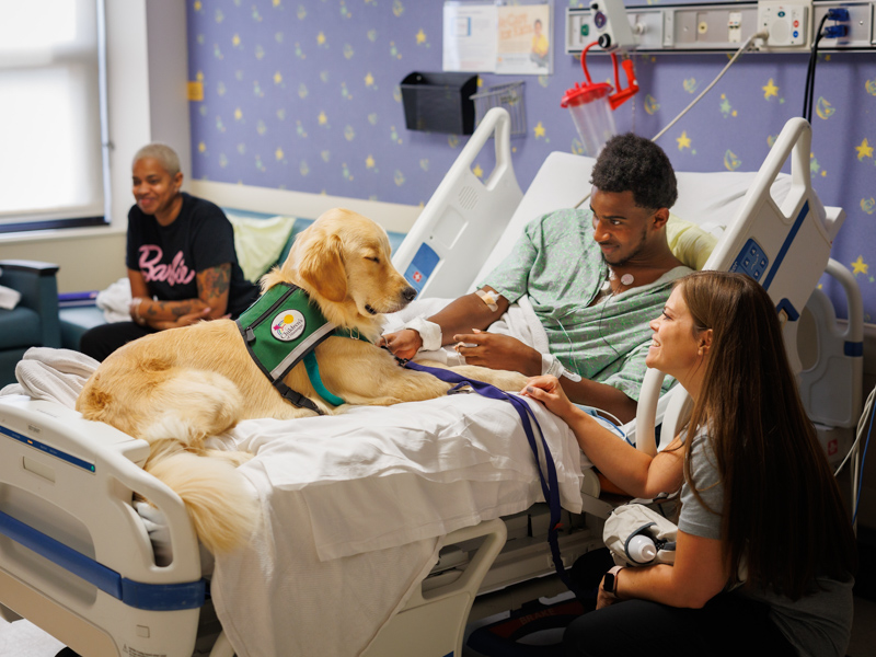 Children's of Mississippi patient Cayden Myers, 15,  of Camden gets a visit from Hollywood and the facility dog's handler, child life manager Cara Williams.