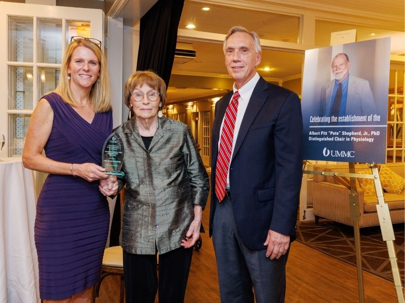 Dr. Genevieve Shepherd Ali, left, and Dr. John Hall, Arthur C. Guyton Professor and chair of physiology and biophysics, present an award to Melissa Shepherd, recognizing her contribution to the Albert Pitt "Pete" Shepherd Jr., PhD Distinguished Chair in Physiology.