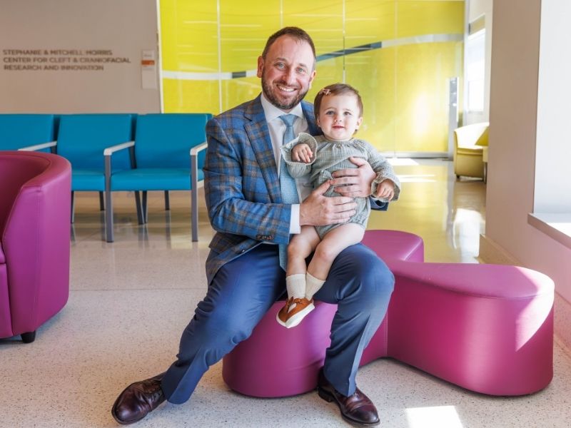 Dr. Ian Hoppe holds patient Mila Medders after a series of plastic surgeries repaired her right ear.