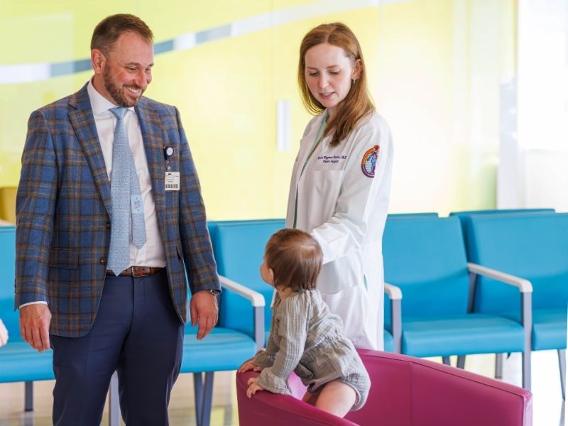 Dr. Ian Hoppe and Dr. Katie Brown visit with patient Mila Medders, who is thriving after plastic surgery to repair an injured ear.