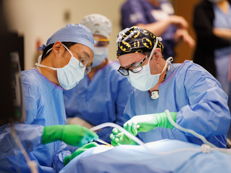 Resident Dr. Jason Lee, left, and Dr. Jeff Carron are shown surgically implanting Landon Forbes' Sentio system.