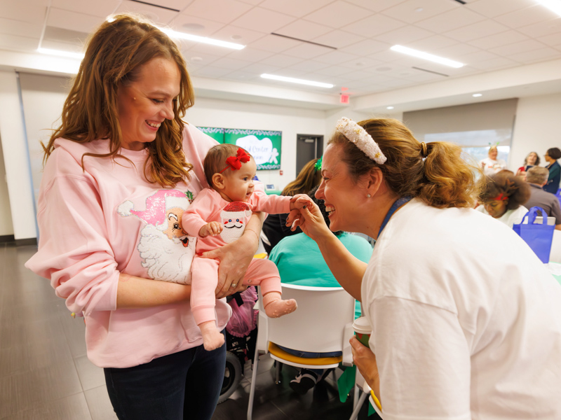 Emily Wells, neonatal nurse practitioner and a former patient of the Center for Maternal and Fetal Health, shows daughter Mary Carter Wells to Dr. Rachael Morris.