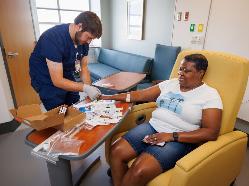 In this 2024 photo, Clinical Research coordinator Thomas Hudson draws blood from Jacqualine Ellis of Flora, a participant in three long COVID clinical trials.