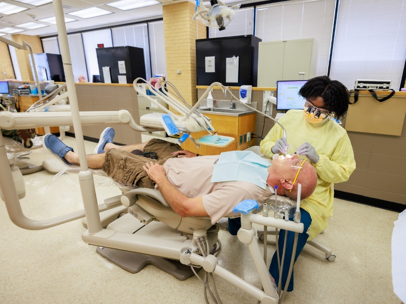 Fourth-year dental student, Adriana Ivy, prepares to place crowns for Mike Armstrong of Pearl.