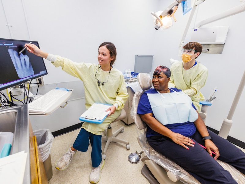 Avery Gibens, fourth-year dental student, walks Tenika Spann of Jackson through her upcoming procedure with partner Jolan Mills, second-year dental student.