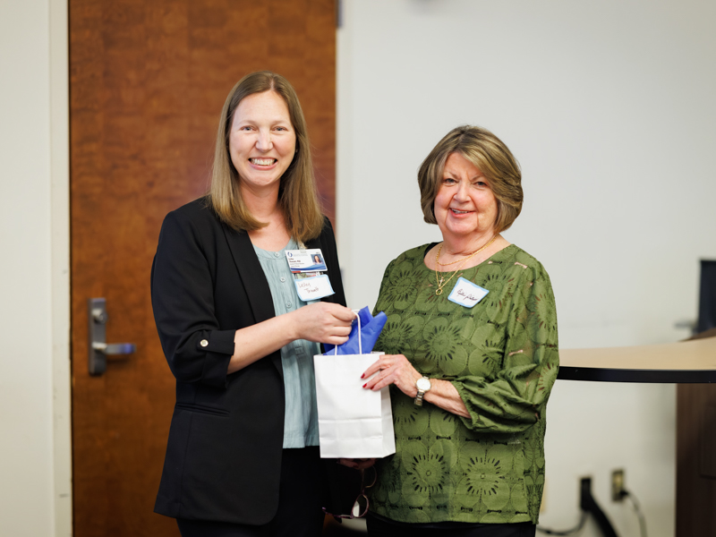 Dr. Billie Rhea Philllips receives a gift bag from Dr.  Lesley J. Thweatt, left, assistant professor of education for the School of Nursing, during the PhD in Nursing program 25th anniversary event.