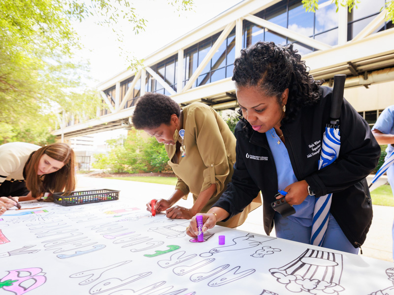 Skyla Wilson, supervisor of the neurophysiology lab, colors an ice cream cone on a poster for Employee Appreciation Week in 2025.