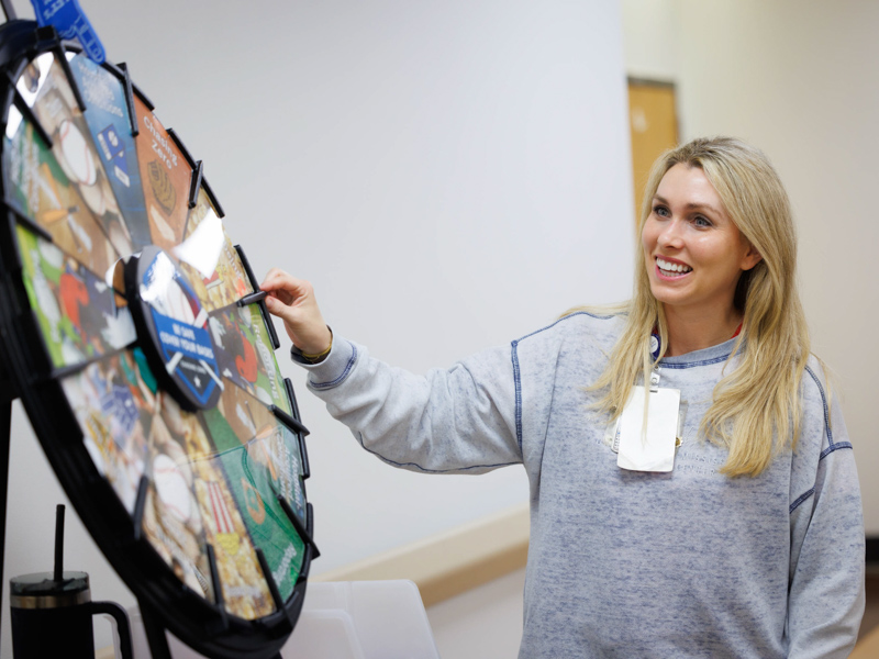 Laurie McHenry, nurse educator, spins the safety wheel for a chance to win prizes as the wheel made a stop at 3 Wiser as part of Patient Safety Week activities in 2024.