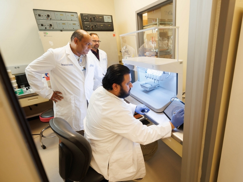 Dr. Mohd Abdullah Khan, seated, Dr. Jawed Siddiqui, looking over Khan’s shoulder, and Dr. Gunjan Sharma observe UMMC’s new 3D bioprinter. The technology helps researchers build models to study how cancer cells behave in surroundings that more closely resemble human tissue.