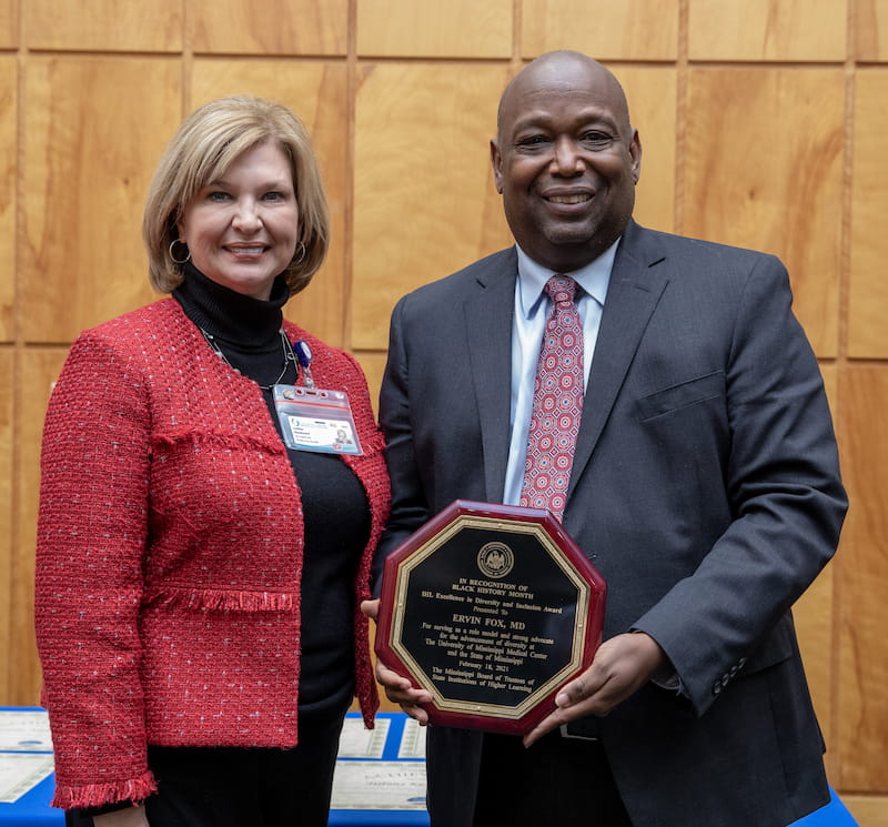 Dr. Irvin Fox holds a plaque. Dr. LouAnn Woodward stands to the left of him.