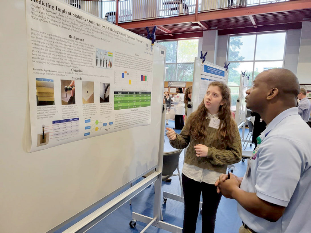 A student explains her presentation poster to an onlooker.