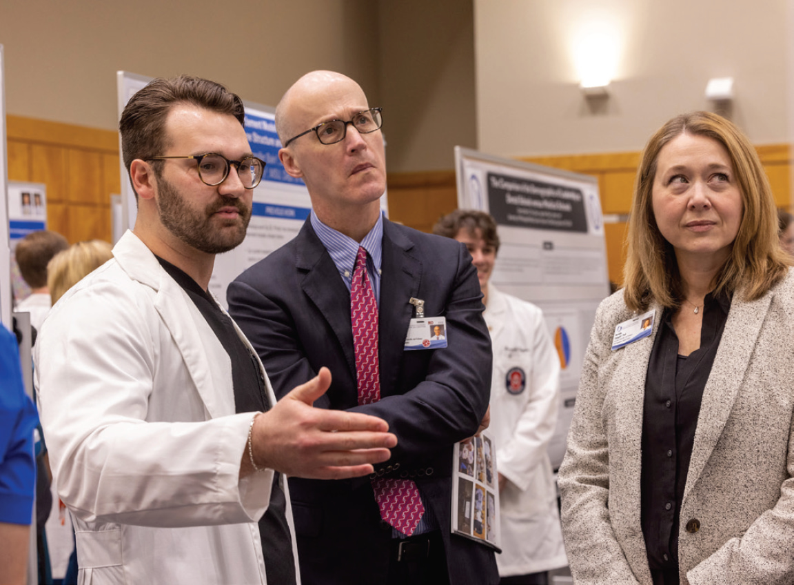 A graduate student explains a presentation poster to Dr. Scott Rodgers and Dr. Natalie Gaughf.