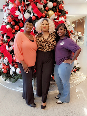 Michelle Brassfield (center) takes a picture with two staff members in front of the Christmas tree at the UMMC School of Medicine.