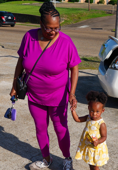An attendee walks while guiding a toddler alongside her.
