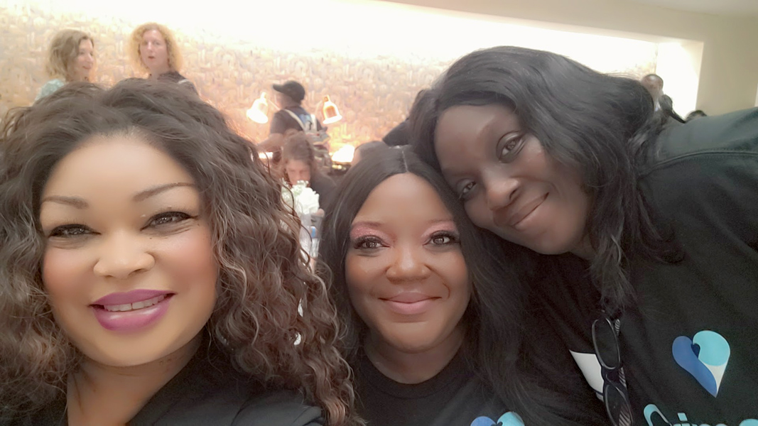 Three participants leaning together for a group photo indoors while wearing matching event shirts.