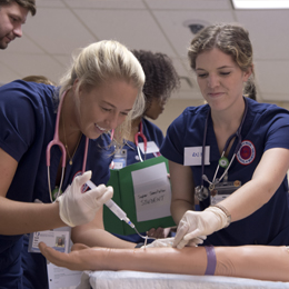 Students work with IV arms during simulation.