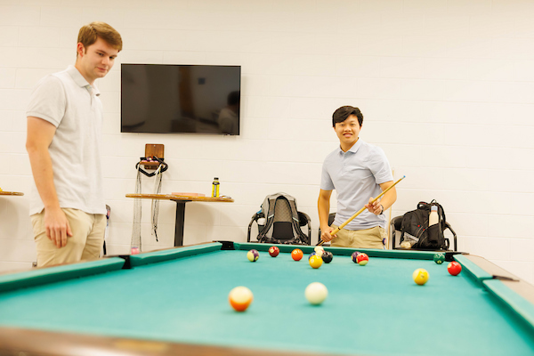 Two students playing pool in the Recreation Center.