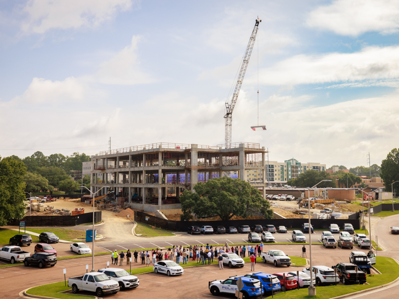 Nursing faculty and UMMC leaders applaud the lifting of the beam to the top of the new School of Nursing, which is set to open next year.